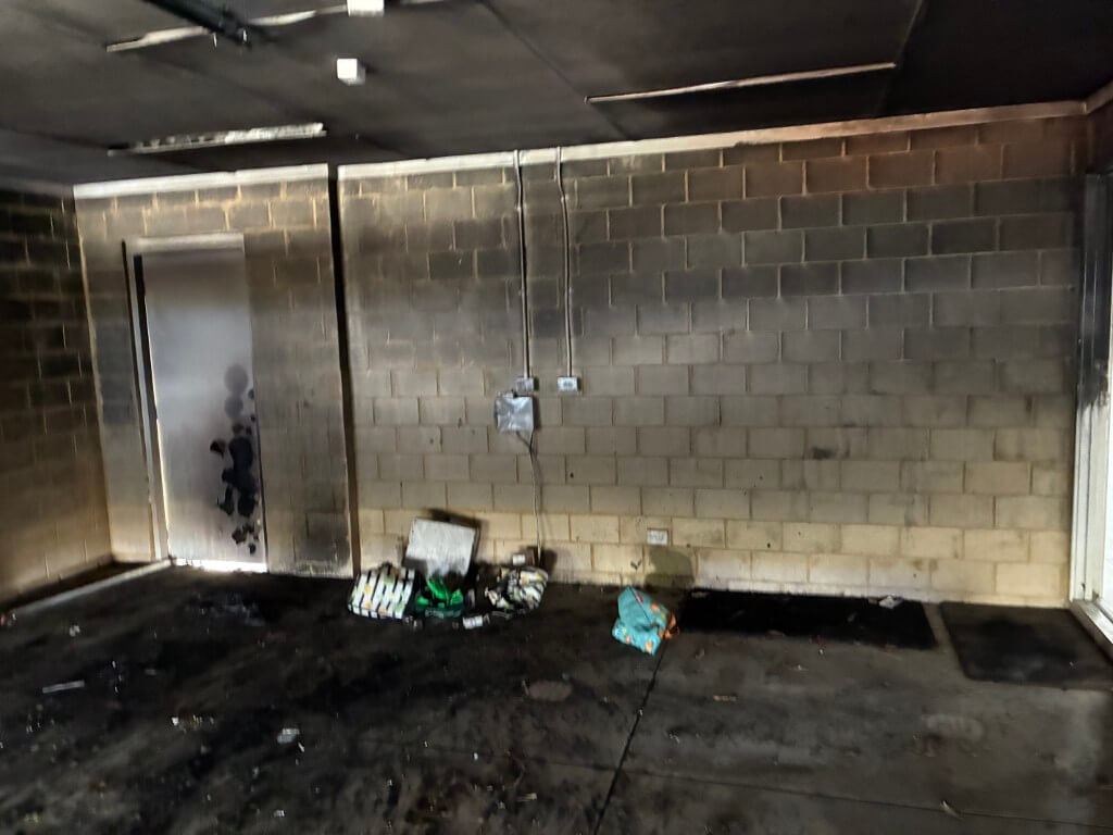 Garage interior blackened with soot and char across the block walls and ceiling after a fire
