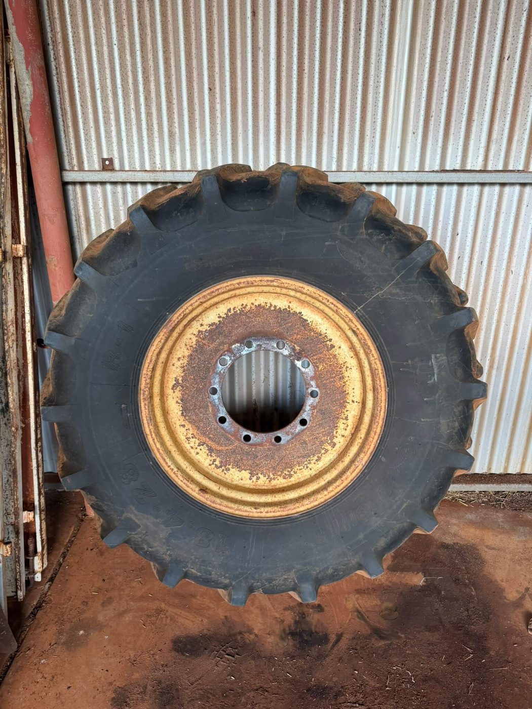 Tractor rim with rust breaking through old yellow paint around the centre and bolt holes before blasting