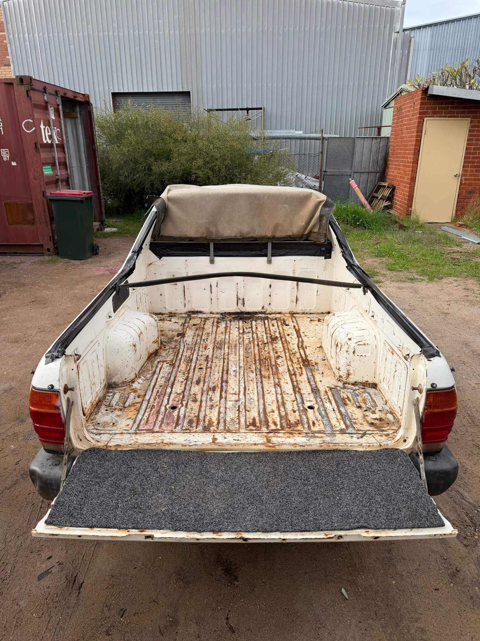 Ute bed with flaking paint and heavy surface rust across the floor ribs before blasting