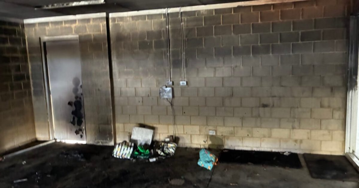 Garage interior blackened with soot and char across the block walls and ceiling after a fire