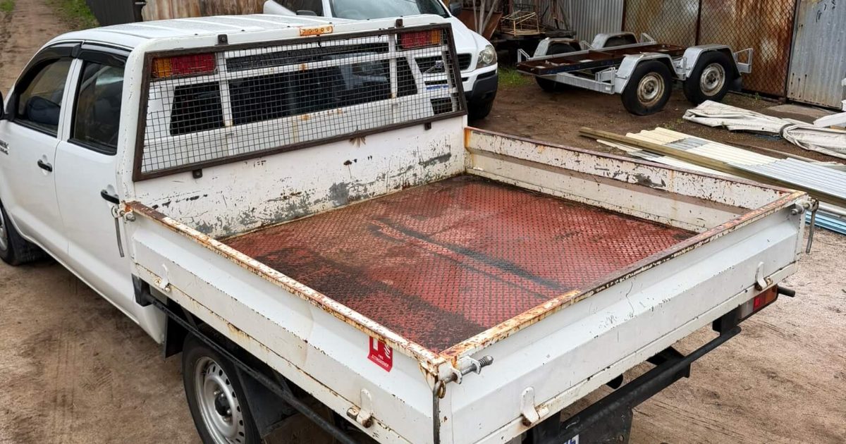 Dual-cab ute tray with rusted drop sides and a corroded checker-plate floor before sandblasting