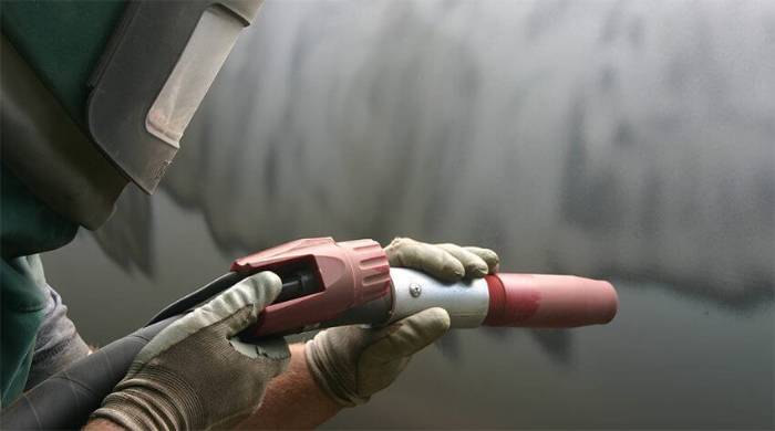 Graffiti tags being removed from a painted brick wall in Perth