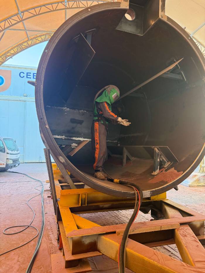 Tank interior, confined space Blaster working inside a large steel tank shell under a WA containment tent